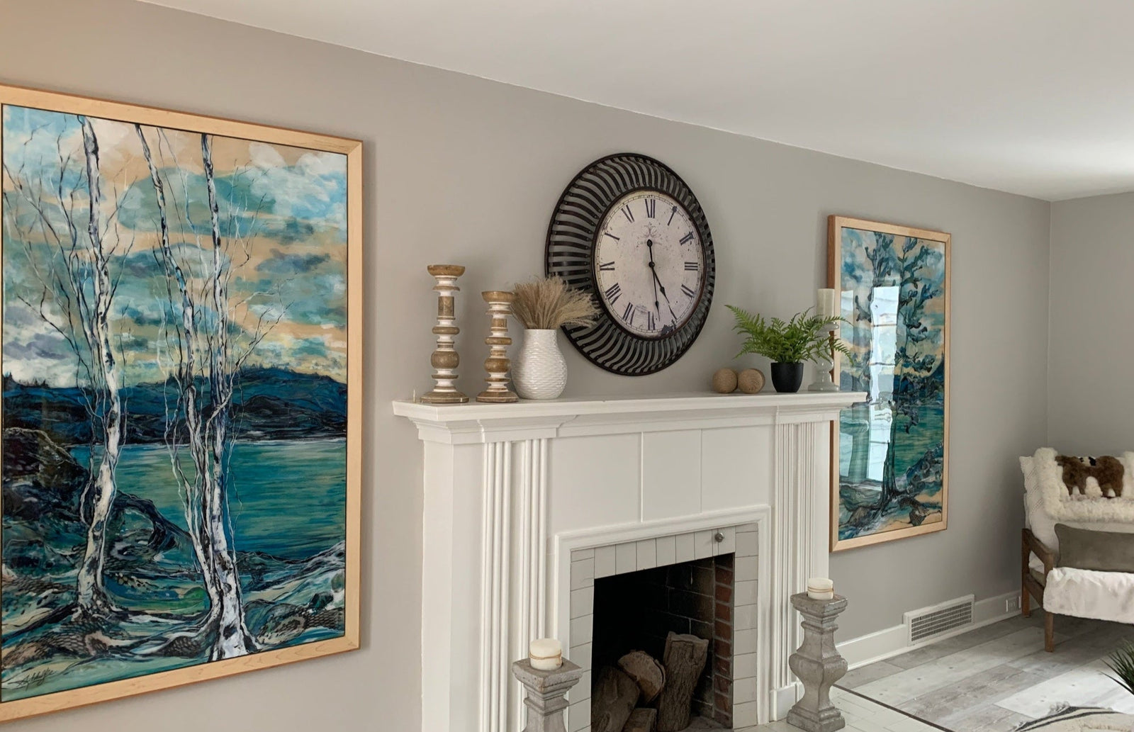 Living room with a fireplace, clock, and artwork on a gray wall.